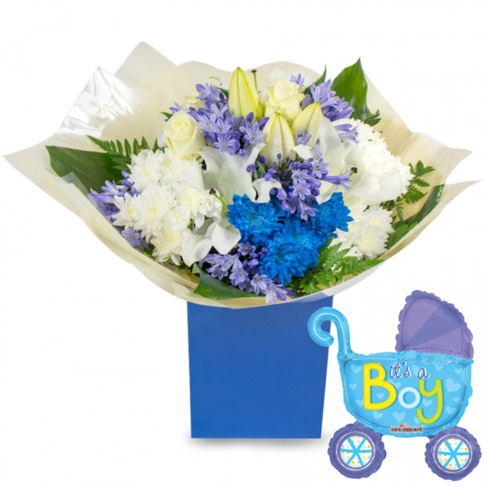 A fresh, thoughtfully composed baby-boy bouquet displayed with a celebratory pram-shaped balloon, described here with the eye of a local Brent Cross florist. The arrangement centers on a dense, rounded grouping of white blooms: classic roses with soft, layered petals, elegant white lilies-several paused between bud and bloom-and plush white chrysanthemums that add volume and a serene softness. Cutting through the whites are electric-blue chrysanthemums and a compact cluster of vivid blue flowers that give the design its joyful, unmistakable blue statement. Scattered among them are small clusters of pale lavender or periwinkle bell-shaped flowers, likely hyacinths, introducing gentle scent and delicate form. Fresh foliage-broad, glossy leaves and light, feathery fern fronds-frames the blossoms and lifts the composition, while the stems are swathed in crinkled, translucent cream wrapping that nestles neatly into a matte royal-blue rectangular gift box for a polished presentation. To the right, a light-blue foil balloon in the shape of an old-fashioned baby carriage completes the scene; it is detailed with darker-blue accents on the canopy and wheels, tiny polka dots and heart motifs, and the phrase It's a Boy in bright yellow and lime-green script. Prepared with neighbourhood care at Brent Cross Flowers, this set feels perfect for a baby shower near Brent Cross Shopping Centre, a hospital visit, or a warm welcome-home delivery to Cricklewood or Childs Hill.