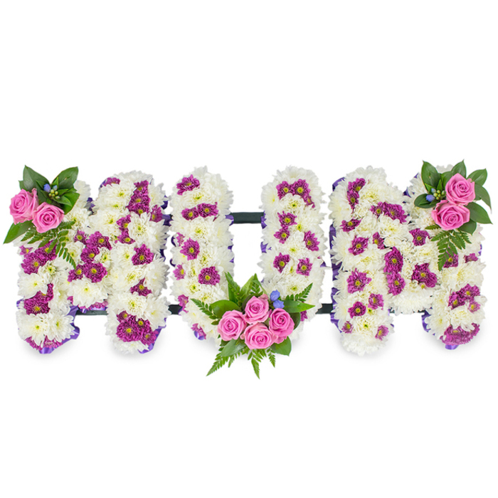 Crafted with quiet care and an eye for texture, this three-dimensional 'MUM' tribute sits against a plain white background so the composition's details are unmistakable. Each of the three letters is built from a dense cushion of immaculate white chrysanthemums, their clustered petals forming a soft, almost tactile surface that speaks of comfort and long-lasting devotion. Scattered through the white are speckles and small patches of rich magenta and purple spray chrysanthemums which create gentle contrast and a patterned depth that prevents the design from feeling flat. The arrangement is punctuated by three touches of bright pink spray roses: a modest cluster at the top left of the first 'M', a larger, more generous bouquet nestled into the lower curve of the 'U', and a mirrored cluster at the top right of the final 'M'. Around these rose groupings, lush dark green foliage - including elegant fern fronds - fans out, and tiny blue accent flowers appear like delicate notes of cool colour. Along the letter edges a slim purple ribbon faintly outlines shape in places, while a thin dark bar connects the letters from behind to maintain structural integrity without distracting from the floral surface. The scent is subtle, a quiet blend of chrysanthemum freshness and the soft sweetness of roses. As a Brent Cross Flowers design, this personalised tribute is shaped for memorial services, chapel displays and wakes across Brent Cross, Hendon and Cricklewood, offering families a dignified, handcrafted expression of remembrance that reads as both traditional and tender.