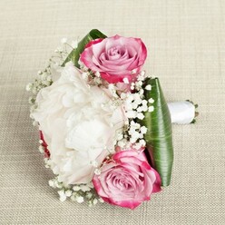 A perfectly poised bouquet rests atop a natural linen background, its palette and artistry reflecting the contemporary elegance of Brent Cross. In this arrangement, radiant pink roses take center stage, their petals shaded from bold candy-pink edges to gentle blush at the core-a compelling visual journey that mirrors the variety found on bustling Broadway or quiet residential lanes. Between them, a lavish white peony blooms, its ruffled petals luxuriously layered, offering a tactile sense of fullness and softness seen in the early spring gardens of Golders Hill Park. The bouquet is accented with clouds of baby's breath, each spray adding tiny, star-like blossoms that introduce lightness and air, lending the entire composition a sense of movement and grace. The deep emerald leaves, glossy and broad, sweep elegantly around the base, grounding the bouquet with sophistication and a rich green vibrancy. A white satin ribbon binds the stems, forming a polished, easy-to-hold handle-ready for a bridesmaid's walk down the aisle or as an elegant highlight for a Brent Cross celebration. Illuminated by diffused daylight, each petal, leaf, and floral accent glows with freshness, expertly arranged by local Brent Cross Flowers artisans. Whether chosen for weddings, special anniversaries, or a classic romantic gesture, this bouquet radiates gentle fragrance, beauty, and uplifting emotion-capturing the heart of the local community.