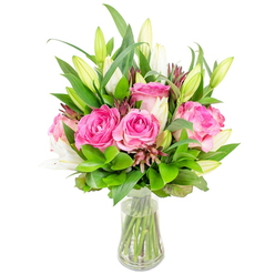 An elegantly composed bouquet of fully opened deep pink roses and poised white lily buds rests in a clear glass vase, the image set against a pristine white background that highlights every petal and leaf. The roses display layered ruffles of blush and fuchsia, each velvety petal curving outward with the confident fullness of roses cut at peak freshness; their fragrance reads as soft and honeyed in the imagination. Interspersed among them are tall white lily buds, some still enclosed like secret notes and others gently parting to reveal pale throats and the first hints of stamens, lending vertical grace to the rounded rose heads. A lavish selection of greenery - from broad, glossy leaves to feathery, lighter-green sprigs - builds a lush backdrop that makes the pinks and whites sing, while subtle burgundy filler buds add a shadowed warmth and textural contrast. The clear vase, with a modestly tapered base, holds pristine water and reveals neatly trimmed stems as a mark of careful floristry. Lighting feels clean and daylight-fresh, as if arranged in a Brent Cross studio near the shopping centre or beside the Welsh Harp reservoir on an early morning, a setting that preserves colour and scent. Thoughtfully prepared for special occasions - birthdays, Mother's Day, anniversaries, or as a heartfelt thank-you - this bouquet conveys quiet celebration and domestic elegance. Brent Cross Flowers might package and deliver this composition across Brent Cross, Cricklewood Broadway, and surrounding neighbourhoods for same-day delivery when freshness matters most.