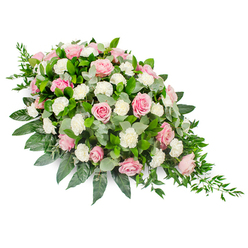 Photographed against a clean white background, this refined sympathy spray reveals a flowing teardrop silhouette, the type of tribute often seen accompanying funeral services around Brent Cross, Golders Green, and Cricklewood. The arrangement is dominated by an abundance of pink roses, their velvety petals unfurling in soft spirals from tightly curled buds into fully open blossoms. Their hues range from the faintest blush to a richer, comforting rose pink, lending the composition a gentle warmth that feels both tender and respectful. Interspersed between the roses are tufts of pristine white carnations and spray carnations, their ruffled petals adding cushioning clouds of texture and brightness. Layered beneath and around the flowers, a thoughtful mix of greenery provides structure and depth: broad, glossy dark green leaves frame the edges and define the teardrop outline, while rounded eucalyptus in a silvery-green tone winds between the blooms, hinting at a soft, calming fragrance. At the narrowing tip of the spray, fine strands of deep green ruscus trail out, creating a delicate cascade that accentuates the sense of flowing movement. The arrangement appears carefully balanced, never crowded yet richly full, echoing the quiet dignity of a well-planned farewell. It conjures the image of resting gently on a casket or placed as a central tribute in a Brent Cross funeral home, where families can focus on its soft colours and soothing lines during moments of reflection. The overall mood is one of quiet luxury and deep sympathy, a floral expression of enduring love and gratitude.