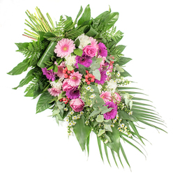 Displayed against a clean white backdrop, this refined funeral spray sweeps in a confident diagonal from the upper left to the lower right, its shape both modern and traditional, echoing the calm pathways around Brent Cross and Hendon. The design centres on large gerbera daisies in two main shades: soft, pastel pink and stronger, fuchsia-toned magenta. Their wide, symmetrical petals and dark centres give the piece a sense of cheerful dignity. Interwoven with these are classic pink roses, their tightly curled petals forming perfect rosettes that symbolise affection and lasting memories. Between the larger blooms, soft white flowers - likely small carnations or chrysanthemums - bring a velvety, ruffled texture, creating a luminous contrast. Tiny daisy-like flowers in white with yellow centres thread through the arrangement, adding a light, dancing rhythm that softens the stronger colours. Bright red hypericum berries are nestled among the petals, their rounded, polished forms adding natural interest and flashes of warm colour. The flowers rest on a foundation of mixed foliage: broad, glossy dark leaves offer structure and shine; fine, feathery fern fronds introduce movement; and cool, silvery eucalyptus leaves bring a subtle, aromatic freshness and a contemporary touch. Long, slim palm leaves extend from the lower right, finishing the spray with a sweeping, trailing effect that helps guide the eye along the design. At the top left, the stems are tidily bound, revealing the craftsmanship of the florist. This arrangement, suited for use as a casket spray or significant sympathy tribute delivered to homes, chapels, or crematoriums around Brent Cross, conveys gentleness, respect, and a comforting farewell.