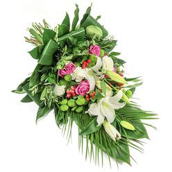 Symbolic and serene, this elongated floral spray is thoughtfully arranged by a Brent Cross florist for meaningful moments of remembrance. White trumpet lilies serve as the arrangement's peaceful core, with their elegant petals and gentle golden stamens representing purity and hope. Each lily is nestled among vivid pink roses-some delicately opening, others still in promising bud-imbuing the bouquet with warmth and gentle nostalgia. Soft white carnations fill spaces between, adding a textural softness that quietly reassures. Embedded in this heartfelt mix are crisp, round santini chrysanthemums in bold green, lending a contemporary edge and energy reflective of Brent Cross's lively community spirit. Sprinklings of gleaming red hypericum berries enliven the composition, while a robust selection of green foliage-glossy folded leaves, light feathery greens, and cascading palm fronds-creates a sense of movement, freshness, and structure. Natural light plays upon every bloom and leaf, drawing out subtle variations in tone and sheen. Perfect for conveying sympathy and respect at farewells or memorials along the North Circular or in local synagogues and churches, this arrangement unites expert craftsmanship with a gentle, local touch and is available for sensitive delivery throughout Brent Cross.