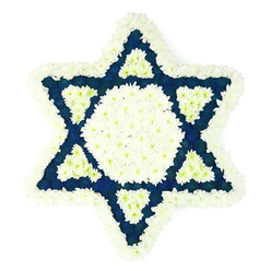 A beautifully balanced Star of David floral arrangement fills the image, captured against a bright white backdrop that highlights every petal and line. The star itself, a traditional Jewish symbol, is rendered in a precise, six-pointed form using a dense carpet of fresh flowers in two main tones: pristine white and a deep, solemn blue. Along the very edge, a wide band of soft white chrysanthemums and similar blossoms forms a plush border, their rounded heads overlapping to create a gentle, cloud-like outline. Within this frame, a central hexagon rests like a calm island, also packed with white blooms, their small petals giving a fine, almost velvety texture. Radiating outward from this centre, the six arms of the star are filled with luxuriant dark blue flowers, adding visual weight and depth, reminiscent of the rich blues often associated with Jewish ceremonial textiles in nearby Golders Green and Brent Cross. At the base of each triangular point, a finely shaped white triangle is set into the blue, producing a repeating motif of white on blue that strengthens the visual rhythm of the Magen David. The arrangement feels still, yet deeply expressive, ideal for a funeral, memorial service, or shiva in the local community, whether delivered to a home just off the North Circular or to a chapel near Brent Cross Shopping Centre. You can sense the care taken by an experienced florist, each flower placed to reflect faith, remembrance, and compassion, offering bereaved families a dignified and meaningful way to say goodbye.