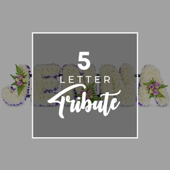 A carefully crafted five-letter floral tribute is the focal point of this photograph, presented against a soft light grey background that allows the details to stand out clearly, just as they might on a display stand at a Brent Cross funeral home. Each letter is sculpted and then generously covered with crisp white chrysanthemums, the small, multi-petalled blooms packed closely together to create a plush, seamless surface. Their snowy colour evokes purity and remembrance, while the texture adds a comforting, almost quilted appearance. Encircling every letter is a deep purple satin ribbon, its rich hue and subtle shine lending definition and a dignified frame to the white flowers. This border traces each curve and corner with precision, giving the tribute a polished, professional look typical of an experienced local florist. Scattered thoughtfully along the letters are dainty floral accents: clusters of pale pink and mauve spray roses, some still tightly furled, others softly opening, nestled among airy green fern fronds and sprigs of foliage. These touches of pastel colour and greenery introduce movement and depth, as though little islands of memory have been tucked into the tribute. The arrangement seems to spell out a personal name, with a clear "J" on the left, followed by "O," "H," and "N" partially obscured in the middle, and an "A" visible on the right. This suggests the piece can be customised for any five-letter word or name, a popular choice for families ordering from Brent Cross Flowers for services in nearby chapels. At the centre of the image, a semi-transparent grey square panel with a neat white outline overlays part of the letters; on it, the phrase "5 LETTER" is printed in crisp white capitals above the flowing script of "Tribute," serving as a discreet guide for those browsing memorial flower options. The overall mood conveyed is gentle, respectful, and personal, ideal for honouring a loved one with a bespoke floral farewell.