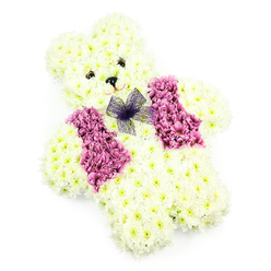 This photograph presents a charming floral teddy bear tribute, carefully designed to look both cuddly and dignified. The figure is seated and fully composed of fresh blossoms, with its entire body covered in tightly clustered white chrysanthemums that form a thick, textured coat. The blooms follow the contours of the bear's round head, pronounced ears, full cheeks, and short, rounded limbs, creating a sense of three-dimensional softness. The face is marked by two small, deep-coloured eyes that peer gently out from the cushion of petals, and a tiny black triangular nose positioned above a very subtle arc of pale pink, hinting at a soft, reassuring smile. Across the front of the bear, a vivid waistcoat in shades of deep pink to magenta is created with more chrysanthemums, carefully arranged into two symmetrical panels that mimic the lapels of a little jacket. This bold swathe of colour stands out beautifully against the white fur, adding warmth and joy to the design. At the neckline, a delicate bow fashioned from sheer purple netting sits gracefully on the chest, its translucent folds and slight shimmer lending an air of playfulness and care. The neutral white background and gentle, even lighting keep the focus entirely on the floral workmanship, highlighting each petal and curve. As an experienced Brent Cross florist, this is the kind of tribute we see chosen for children's funerals, baby memorials, or tender farewells in the local area, from services near Brent Cross Shopping Centre to small family gatherings along Golders Green Road, offering a floral symbol of innocence, love, and remembrance.