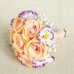 Elegance flourishes in this hand-tied bouquet, set against a soft beige linen backdrop that echoes the understated style of Brent Cross occasions. Nestled at its heart are lush, open roses in peach, apricot, and whisper-pink, their layered petals inviting the eye to linger-much like a tranquil promenade through Clitterhouse Playing Fields. Around these, ruffled white lisianthus, outlined softly in lavender-purple, provide a modern pop of colour, while delicate clouds of gypsophila weave subtle movement and airiness throughout. Each stem is neatly wrapped with a peach-pink ribbon, finished with understated pearl accents-evoking the touch of skilled Brent Cross florists. The arrangement's round, compact shape embodies both charm and sophistication, making it a favoured choice for bridesmaids, engagement parties, or as a refined centrepiece for North London gatherings. With every detail attended to, this bouquet radiates a sense of hope and festive anticipation, tailored for moments of joy across Brent Cross.