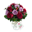 A close-up portrait of a luxuriously rounded bouquet where deep crimson and velvety burgundy roses sit cheek-by-jowl with soft lavender and dusty purple roses, each bloom open with unfurling petals that catch the light. The arrangement reads rich and tactile: the red roses offer a satin sheen while the lilac blossoms lend a gentle coolness, and dark glossy foliage - likely Ruscus or Salal - threads between the blooms to give the composition depth and a living green frame. Scattered like tiny jewels through the massed heads are bright red-orange rose hips that add a rustic, autumnal crunch of colour and a slightly matte texture against the petal silk. The flowers are set into a bulbous mercury glass vase, its silvered, crackled surface reflecting and softening highlights; a strand of natural raffia is tied around the neck, bringing a handcrafted, cottage-chic accent. A small white rectangular gift tag hangs forward from the tie, bearing a simple stylised rose illustration and space for a message. Photographed on a brilliant white background, the bouquet's tones read clearer and more saturated, suggesting freshness and careful handling. I imagine the scent as quietly heady - warm damask rose with green undernotes from the foliage - and the weight of the arrangement as reassuring in the hands. This composition feels intimate and romantic, equally suited to an anniversary or a thoughtful gift, and it has the considered polish you would expect from a neighbourhood Brent Cross florist preparing flowers for delivery around local streets like Cricklewood Broadway and the area near Brent Cross Shopping Centre.