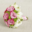 Placed horizontally on a light beige, subtly textured cloth, this hand-tied bouquet appears as though it has been carefully set down between portraits on a Brent Cross wedding day. The arrangement is composed with a florist's eye for balance, starting with the lush pink roses that dominate the left and central sections. Each rose is fully open, revealing overlapping petals that shift in tone from a soft, delicate blush near the center to more saturated fuchsia and magenta at the edges, giving the flowers a rich, almost velvety depth. Tucked closely among them, rounded domes of lime green button chrysanthemums add a surprising spark of colour. Their tiny, tightly packed florets create a pleasing, bumpy texture that contrasts beautifully with the smooth rose petals, lending the bouquet a cheerful, modern feel that suits celebrations around Brent Cross and Cricklewood. To the right, a generous cluster of white lisianthus opens in ruffled, layered blooms, with some flowers fully unfurled and others only just beginning to part their petals. The interplay of creamy white and pure white tones, along with the upright, unopened buds, introduces lightness and a sense of movement, as if a soft breeze from nearby Brent Reservoir had just brushed past. The stems are gathered in a comfortable handle, wrapped in blush pink satin ribbon that lies flat and smooth. Around this, delicate strands of white pearls are coiled with precision, their gentle sheen adding a classic bridal touch that bridges tradition and contemporary style. Soft, even lighting enhances the bouquet's colours and textures, creating a mood of romance, serenity, and thoughtful craftsmanship.
