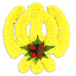 A sculpted floral Khanda rendered entirely in sunlit yellow blooms fills the frame against a pristine white backdrop. The emblem's circular chakkar, central double-edged khanda and the two crossed kirpans are all carefully built from thousands of small, tightly packed bright yellow chrysanthemums, their layered petals forming a soft, almost velvety surface that catches a cool, studio light and creates gentle highlights across the curves. At the geometric heart of the symbol sits a concentrated cluster of deep blood-red roses - five tightly furled heads - cradled by a ring of glossy, dark green fern fronds that add both contrast and a feathered texture. A faint grey shadow beneath the tribute confirms it is a three-dimensional piece, likely a freestanding wreath or ceremonial board piece intended for a memorial or religious occasion. The overall mood is one of solemn respect, the yellow conveying warmth and remembrance while the red roses bring a quiet note of reverence and love. Up close you can almost sense the dry, sweet scent of chrysanthemums blended with the heavier, velvety perfume of the roses, and the cool, green scent of the ferns. As a London florist experienced with cultural commemorations around Brent Cross and nearby Cricklewood Broadway, I picture this piece in a gurdwara doorway or placed near a service at Fryent Country Park community halls - an emblematic tribute that balances craftsmanship, colour, and spiritual symbolism with thoughtful simplicity.