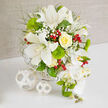 Set on a crisp white tabletop, a luxurious floral arrangement unfurls against a softly mottled beige background, as if captured in the calm light of a Brent Cross morning. At its heart, white Oriental lilies open generously, their petals wide and gently ruffled at the edges, revealing subtle freckles and tall, graceful stamens that add both depth and delicacy. Nestled among them, a beautifully formed yellow rose glows with creamy petals wrapped into a neat, central swirl, bringing warmth and a suggestion of sunshine into the composition. From the right side, a cascading strand of pristine white Phalaenopsis orchids drapes downward in an elegant curve, each bloom smooth and velvety with small yellow centres, trailed by clusters of tight green buds that promise future blossoms. Around these focal flowers, bright green dianthus puff up like tiny moss cushions, their rounded shapes and soft texture giving the bouquet a playful, tactile quality, enhanced by wisps of light, feathery greenery woven throughout. Scattered clouds of white baby's breath soften transitions between blossoms, adding a romantic, airy veil, while glossy red hypericum berries stand out like little garnets, injecting festive colour that recalls winter celebrations in homes around Brent Cross. The flowers are held together in a low white woven basket, just visible at the base, its gentle wicker pattern mirrored in two decorative white spheres placed to the left, completing a stylish, coordinated vignette. This image evokes refined wedding arrangements or sophisticated table décor, the sort of carefully orchestrated design a local Brent Cross florist would create for same-day delivery to nearby venues, from intimate restaurants to elegant gatherings around Hendon Way.