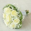 Infused with the gentle romance and celebration that fills Brent Cross on a joyful day, this bouquet of soft white and subtle yellow roses is nestled among dreamy clouds of baby's breath, all aglow atop a subtly woven beige cloth. Each rose appears to hold a quiet luminosity, their creamy petals softly unfurling as if catching early sunlight peeking through Hendon's leafy avenues. The elegant, feathery texture of gypsophila surrounds every bloom, giving the bouquet a weightless, almost ethereal character-like a delicate promise newly spoken. Dynamic arcs of slender green bear grass bring a whisper of movement and a subtly modern touch to this otherwise timeless arrangement. The stems, carefully fastened in lustrous silver ribbon and meticulously detailed with rows of radiant white pearls, are gathered in a handle designed to invite a loving touch. Natural green tips peek out from beneath the pearl wrap, showcasing freshness and expert handcraft. Whether cradled by a bride or offered to honour a cherished friend, this bouquet's serene tones and masterful composition are a celebration of Brent Cross floristry, carrying with it every tender wish and joyful hope for the occasion.