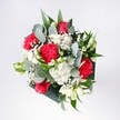 A hand-tied bouquet of rich red roses, ruffled crimson carnations, and soft, snow-white daisies rests against a neutral background, glowing as if caught in gentle North London morning light. Each velvety rose opens confidently at the centre, its deep, romantic red drawing the eye, while clusters of daisy-like white chrysanthemums ring the arrangement with a bright, innocent freshness. Between them, the carnations add texture with their almost feathery, folded petals, echoing the same passionate red tones but with playful movement and depth. Wisps of baby's breath weave throughout, tiny white florets floating like a light mist, softening the stronger colours and lending the whole bouquet an airy, celebratory feel. Around the blooms, eucalyptus stems arc outward in cool grey-green, their rounded leaves and subtle, herbal fragrance giving a modern twist. Deeper tropical foliage in glossy, dark green frames the flowers, grounding the composition and adding contrast without overwhelming the central reds and whites. The bouquet looks carefully balanced-neither rigid nor wild-suggesting the calm skill of an experienced florist who understands how flowers behave once they're in a vase on a kitchen table overlooking Brent Cross or a sunny living room near the shopping centre. The arrangement feels perfect for a day of congratulations, a welcome-home surprise, or simply brightening a favourite corner, the kind of bouquet you might have delivered locally to mark a small but meaningful moment. Its blend of colour, texture, and gentle fragrance suggests a picture of joy and reassurance, like a deep, steady breath of happiness captured in flowers.