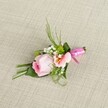 A petite, handcrafted boutonniere from Brent Cross sits lightly offset on a warm beige linen background, its woven texture reminiscent of the inviting interiors found throughout Golders Green and the local Brent Cross area. Central to its design is a delicate rosebud in pastel pink, petals tightly wound and elegantly ascending, radiating gentle freshness and romance. Accompanying the rose is a lighter peachy-pink alstroemeria blossom, unfurling to reveal subtle gold and fine markings that suggest artistry and thoughtful detail. Soft clusters of white baby's breath nestle throughout, their cloud-like forms providing contrast against small, vibrant green cushion mums. This fresh palette is completed by an array of greenery: slender, dark grasses and folded, broad leaves assembled to give structure and natural charm. Anchoring the stems, a luminous fuchsia pink satin ribbon is tied in a simple, graceful bow, its glint reflecting a spirit of joyous occasion. The boutonniere's arrangement, gently illuminated, highlights every curve and colour, inviting admiration and a sense of celebration perfect for weddings, proms, or commemorations in Brent Cross. The work captures both the care and local expertise defining Brent Cross Flowers, prepared to deliver beauty and elegance, one meaningful accessory at a time.