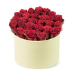 From a slightly elevated, three-quarter perspective, Brent Cross Flowers presents a sumptuous arrangement: a round, pale cream box with a smooth matte finish that frames a dense dome of approximately two dozen velvety crimson roses. The tightly furled petals are in prime bloom, and the blooms rise just above the rim, creating a lush, sculptural mound of red with subtle hints of green foliage peeking between heads for natural contrast. The cylindrical box, with its refined hat-box silhouette, exudes premium feel, marrying contemporary design with timeless elegance. Set against a white background, the arrangement commands attention and invites closer inspection of the petals' satiny texture and the silk-like gleam of the blooms. This image speaks of romance, devotion, and thoughtful gifting, a perfect visual for anniversary features, Valentines Day ideas, or premium flower delivery. In the Brent Cross area, this box arrangement is a signature gift choice, often delivered with care to doorstep celebrations across Hendon, Golders Green, Cricklewood, and nearby NW neighbourhoods. Brent Cross Flowers takes pride in careful stem placement so the dome remains perfectly balanced, and every leaf browns away to leave the red blooms uninterrupted. The scent would be floral and fresh in real life, while the presentation promises a moment of quiet luxury. It's a visual story of love, suitable for articles about couples milestones, or as a luxurious present that says you've gone to great lengths to celebrate a special occasion.