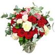 A richly romantic rose arrangement fills a clear glass vase, photographed against a seamless white background so that all attention rests on the colours and curves of the flowers. The bouquet brims with deep red and vivid scarlet roses, some in neat buds and others fully opened, their velvety petals unfurling in layered whorls that seem to spill emotion and warmth. Intertwined with these bold blooms are creamy white and ivory roses, a few kissed with soft pale pink along their edges, casting a gentle light across the darker tones and introducing a sense of balance and tranquillity. Tucked between the larger roses are clusters of small, bright pink filler flowers, likely resembling mini carnations, their petite petals adding a different rhythm and a playful shimmer of colour. The arrangement is completed with abundant blue-green eucalyptus, its rounded, slightly silvery leaves weaving gracefully among the blooms and suggesting a refreshing, aromatic presence. Dark green leaves and occasional silvery-green foliage provide depth and structural support, making the bouquet appear full, round, and impeccably composed. The clear glass vase has a subtle, bulbous base that narrows toward the neck, holding the stems firmly while revealing their natural lines and the clear water at the bottom. With no other visual distractions, the snow-white background intensifies the reds, whites, and greens, allowing every petal and leaf to stand out crisply. The image evokes a sense of intimate celebration, ideal for anniversaries, declarations of love, or thoughtful same-day flower deliveries to homes and offices across Brent Cross and the surrounding streets.