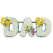 A large, three-dimensional mournful tribute spelling the word DAD in freestanding capital letters, each letter entirely formed from a dense bed of pristine white spray chrysanthemums that give a soft, pillowy texture and a clean, quiet scent. The outer and inner edges of every letter are precisely trimmed with a ruffled, deep green satin ribbon or narrow foliage which acts like a crisp frame against the white blooms; behind the group you can see slim, dark green metal support bars running horizontally, anchoring the letters together and giving the piece a stable, architectural presence. On the left-hand 'D' a bright cluster of sunlit yellow roses-three to four in full bloom-is nestled with tiny white filler blooms, such as freesias or gypsophila, and glossy green foliage; two long, bare green stems arch gracefully from this spray and reach diagonally toward the centre, drawing the eye to the middle letter. The central 'A' carries a more contemplative accent low on its left diagonal: two trumpet-shaped calla lilies in a deep purple or burgundy hue, their elegant curves surrounded by small white accents and soft greenery, offering a sophisticated, reverent focal point. The right-hand 'D' mirrors the left with a matching cluster of cheerful yellow roses and white fillers on its upper curve, balancing the composition. Presented against a clean white backdrop in soft, neutral light, this arrangement reads as a heartfelt memorial - a sympathetic, bespoke tribute designed to comfort families remembering a father, and especially suited for funerals or memorial services in Brent Cross and the neighbouring communities of Cricklewood and Hendon.