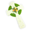 A softly textured, handcrafted Celtic cross made from off-white cream yarn sits photographed against a bright white backdrop, its rounded arms and shaft formed from careful crochet stitches that give the piece a gently pillowed surface. Rich emerald-green yarn is worked into the design to trace the outer edges of each arm and to define the circular ring at the cross's centre, producing a striking, almost embroidered knot-like pattern that calls quietly to Irish heritage. At the very heart of the cross three tiny, yellow-orange rosebuds-delicately crocheted or affixed fabric blooms-are grouped together and accented with a few small, deep-green felt leaves, bringing a touch of warm colour and visual focus to the otherwise neutral textile. Soft studio lighting reveals the subtle loft of the yarn, the tiny stitch shadows, and the handcrafted irregularities that make this ornament feel personal and tender, as if stitched by a neighbour at a Brent Cross craft fair. The overall impression is one of homely reverence: a decorative keepsake that blends religious symbolism and folk craft, suited to a mantel, a memory box, or a quiet corner of a remembrance table. You can almost sense the woolly, comforting texture beneath the fingertips and the faint, home-knit warmth of the materials; there is no overpowering scent, only the quiet suggestion of handmade care. As a local florist who often pairs small handmade tokens with floral tributes for families across Brent Cross, Cricklewood and nearby Hendon, I imagine this piece alongside sprigs of preserved greenery or pinned to a sympathy cushion for a service, offering a gentle, durable expression of condolence and cultural connection.