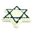 A large Star of David composed entirely from fresh flowers fills the frame, presented against a simple, clean white background so its symbolic form stands out without distraction. The tribute is crafted from an abundance of small chrysanthemums and similar multi-petalled blossoms, giving the surface a lush, cushion-like texture that looks soft yet meticulously ordered. A wide outer band of snowy white flowers draws the six-pointed silhouette with clear, gentle edges, while the central hexagon and inward-facing triangles are also densely packed with white blooms. This central field glows quietly, evoking peace and purity. Overlaying this, the two classic interlocking triangles of the Magen David are expressed in deep navy blue flowers. Their rich, velvety tone creates strong, decisive lines that contrast dramatically with the surrounding white, making the star instantly recognisable as a Jewish symbol. The lighting is soft and even, highlighting the natural variation in petals without breaking the symmetry of the design. A floral piece like this would be well suited to a Jewish funeral or memorial around Brent Cross, whether placed beside the ark in a synagogue near Golders Green Road or brought to a shiva house off the North Circular as an expression of shared mourning. The blue and white palette gently echoes the colours of the Israeli flag, tying personal grief to a wider sense of heritage and community. Overall, the arrangement conveys dignity, respect, and enduring faith, providing a serene, meaningful presence during a difficult and emotional farewell.