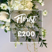 In the Brent Cross studio, a stunning, lush white-and-cream floral spray unfolds in quiet, elevated elegance. The arrangement centers on soft white roses, some shyly closed in buds, others unfurling velvet petals into creamy circles. Surrounding them, voluminous clusters of hydrangea build a fluffy, cloud-like mass, while slender stems of white sweet peas cascade down the length of the spray, adding movement and a whisper of perfume. Interspersed throughout are delicate Nigella flowers--Love-in-a-Mist--its green centers and feathery, lacy petals bringing architectural charm, echoed by feathery foliage that frames the blossoms. The greens vary from broad, deep evergreen leaves to lighter variegated tones, with fine fronds and curling tendrils that trail toward the base, giving the bouquet a garden-fresh, natural feel and a sense of graceful lift. Rustic, woody stems emerge from the bottom, enhancing the spray's artful cascade. At the heart of the image lies a crisp white square frame bearing the script Florist Choice, followed by the bold uppercase CHOICE SPRAY, and finally the prominent ?200 in strong numerals. The soft beige background makes the whites glow, underscoring the bouquet's refined quality. Crafted by Brent Cross Flowers to be worn for remembrance, celebration, or a stand-alone centerpiece, this spray exudes elegance and versatility. It speaks of careful craftsmanship, available for same-day delivery across Brent Cross, Cricklewood, Golders Green, and nearby NW London streets.