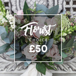 A hand-tied bouquet captured in soft daylight, where the harmony of soft blush garden roses and silvery-blue eucalyptus creates a quietly romantic tableau. The roses, their petals unfurling in gentle spirals, are peppered with bright white berries-snowberries or hypericum-that lend cheerful punctuation and a crisp, clean highlight against the dusted greens. Delicate sprays of tiny white filler flowers, like waxflower or astrantia, thread through the composition, giving the arrangement an airy, almost meadow-like texture that contrasts pleasantly with the denser rose heads. Narrow green-and-white flower spikes peek from the left and right edges, adding vertical movement and a hint of architectural form reminiscent of snapdragons. Subtle touches of deeper pink and burgundy blooms nestle between stems to provide depth and warmth, while the eucalyptus leaves fan out in cool, muted tones and offer that characteristic, calming scent when leaned into. The stems are gathered in a classic hand-tied style and finished with a cream satin ribbon at the base, suggesting a bespoke, tactile finish you can feel in the hands. The bouquet rests on an ornate, distressed cream console with carved detail, the neutral backdrop softening into a pale blur so the colours sing. This arrangement radiates calm refinement-ideal for a milestone birthday, a warm new-home welcome, or a thoughtful 'just because' delivery across Brent Cross and neighbouring Cricklewood. A seasoned florist would describe it as tactile, balanced, and intentionally composed to be both soothing and enlivening, a bouquet that brings the scent of a cutting garden into a quiet London living room.